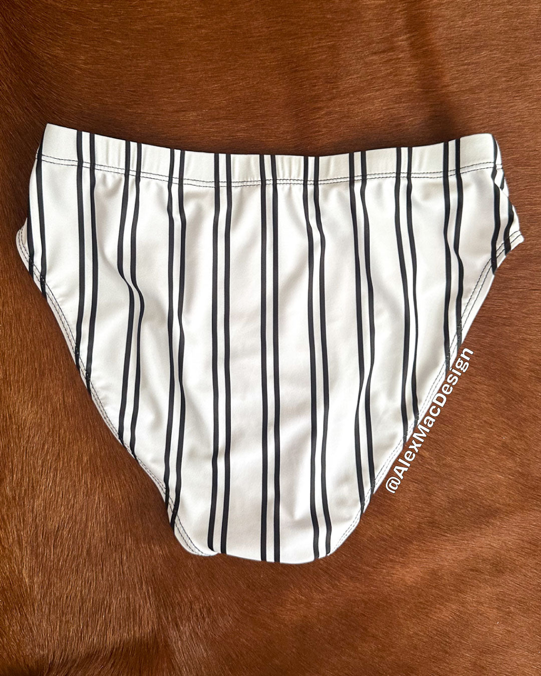 White swim brief with black stripes on a brown surface