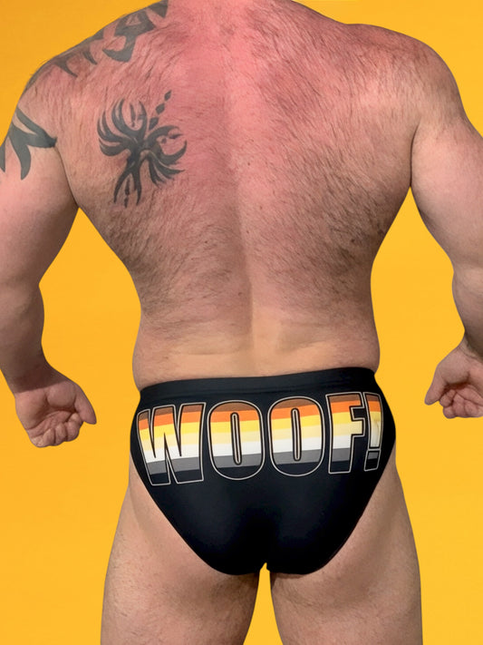 Person wearing black swim brief with 'WOOF!' text on a yellow background